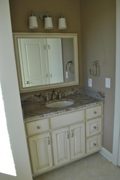 Bathroom vanity with a cream-colored cabinet, granite countertop, and mirror.