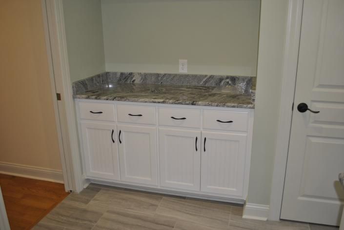 White cabinets with granite countertop in an alcove between doors.