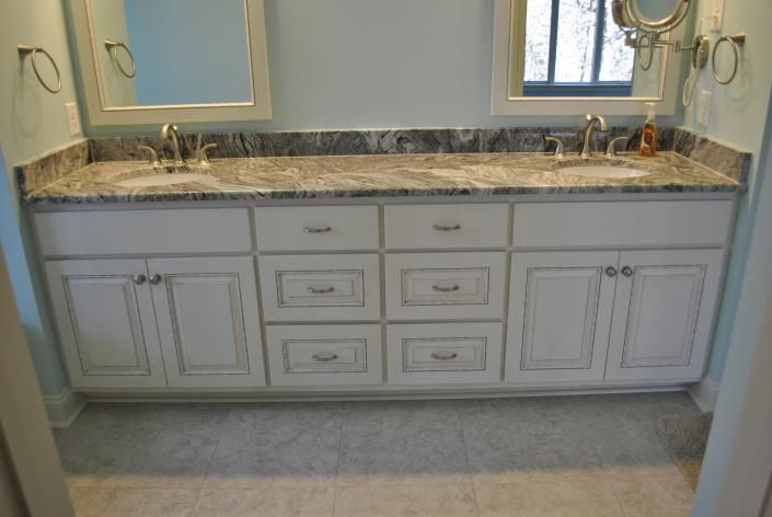 White double bathroom vanity with gray granite countertop, blue walls, and two mirrors.