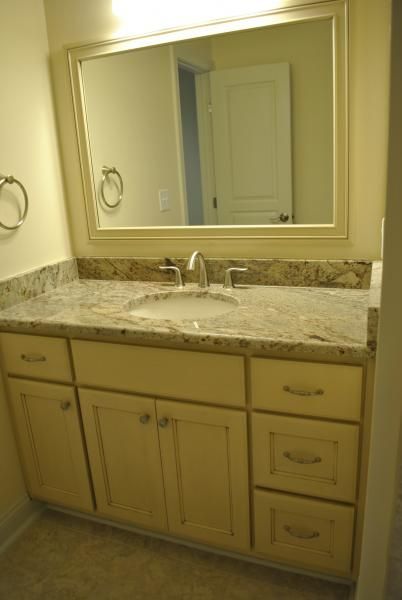 Bathroom vanity with beige cabinets, granite countertop, and mirror.