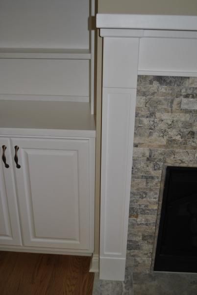 White cabinets and fireplace with stone surround.