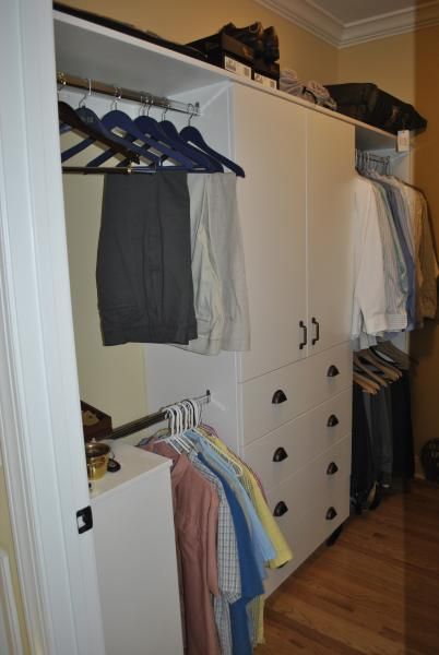 White closet with clothes hanging. Drawers below, wooden floor.