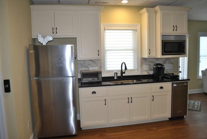 Small kitchen with white cabinets, stainless steel appliances, and black countertop.