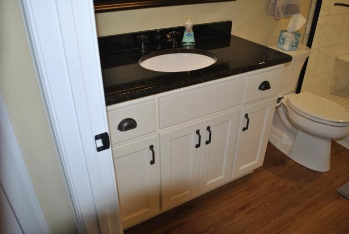Bathroom vanity with black countertop and white cabinet, next to a toilet.