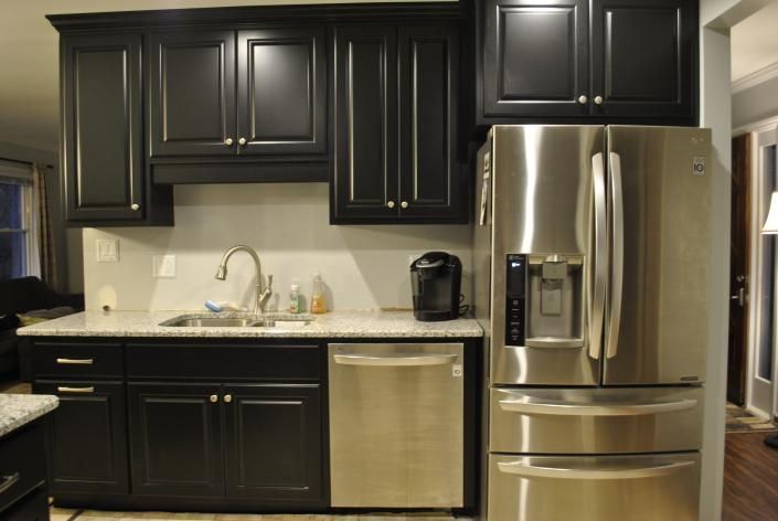 Kitchen with black cabinets, stainless steel appliances, and white countertop.