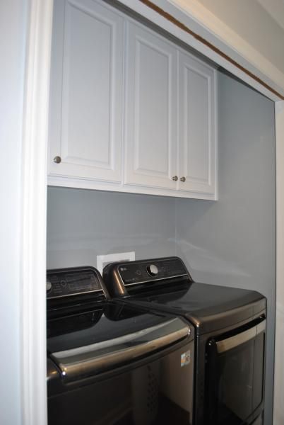 Laundry room with black washer and dryer, white cabinets.