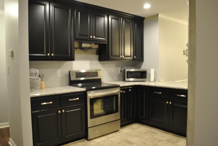 Black kitchen cabinets with stainless steel appliances and light countertops.