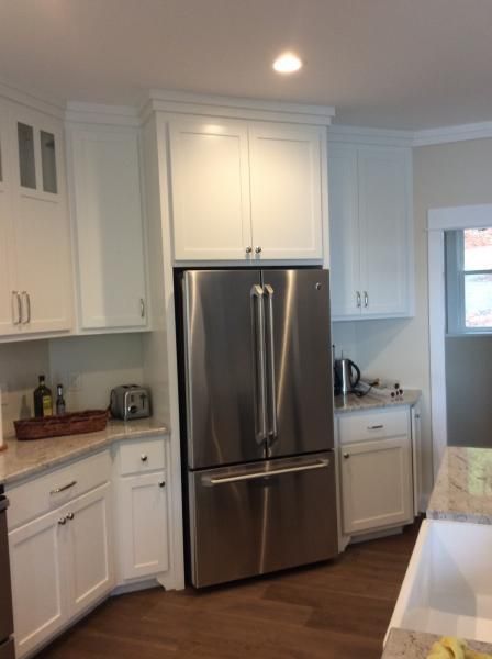 White kitchen cabinets surrounding a stainless steel refrigerator.