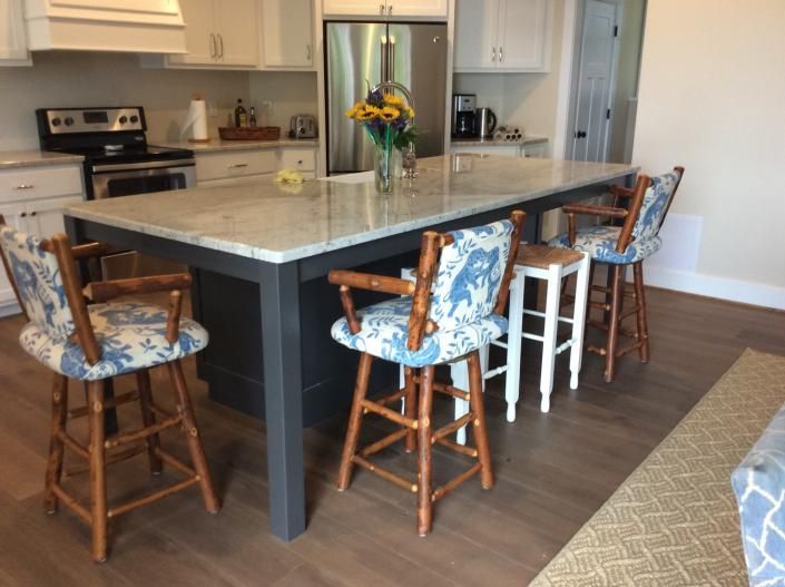 Kitchen with island, granite countertop, bar stools. Dark gray island base, light cabinetry.