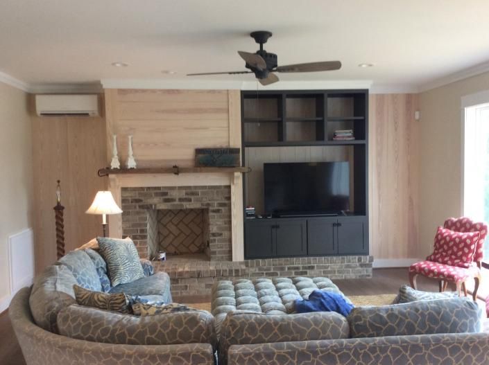 Living room with brick fireplace, built-in shelves, TV, gray couch, and red chair.