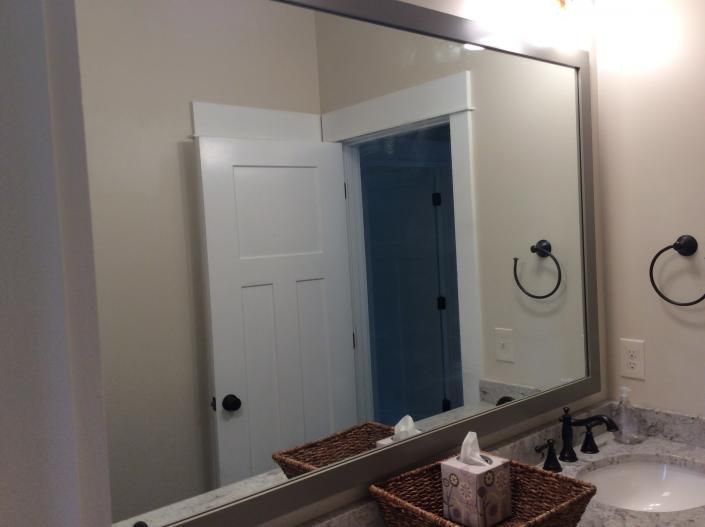 Bathroom mirror reflecting a white door, tissue box, sink, and black fixtures.