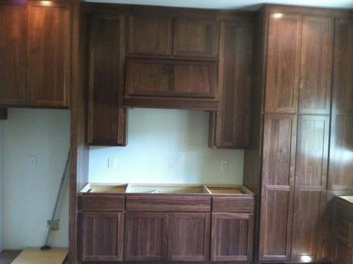 Kitchen cabinets, dark wood, installed on wall, ready for countertops and appliances.