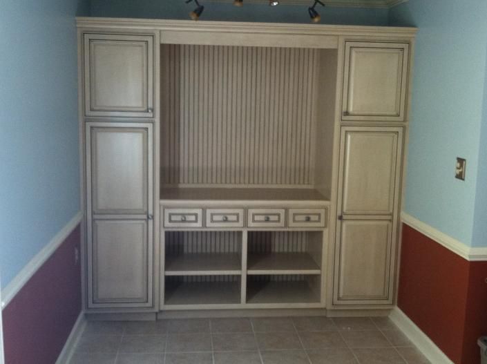 Built-in white cabinet unit with storage and display sections, set in a room with blue and red walls.