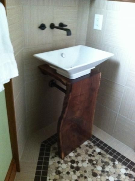 Bathroom with a white square sink on a wooden stand. Black faucet. Tiled walls and floor with mosaic corner.