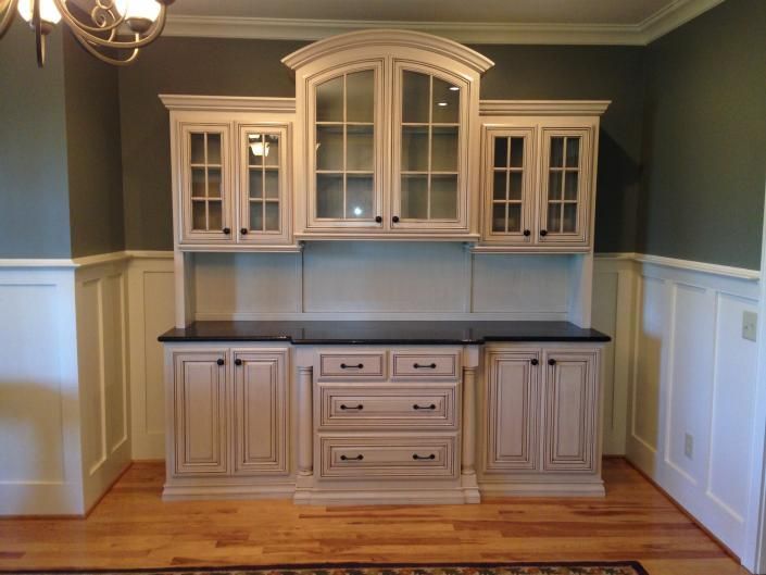 Built-in cream-colored cabinetry with dark countertop and glass-door upper cabinets in a dining room.