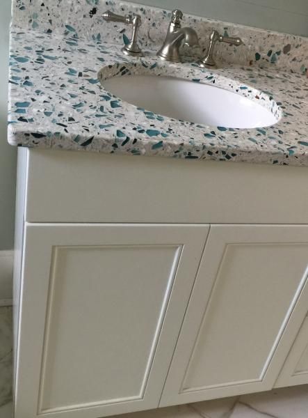 White bathroom vanity with oval sink, blue-speckled countertop, and silver faucet.