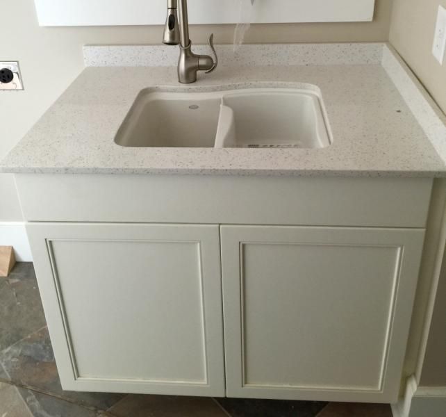 White cabinet with double sink, faucet, and speckled countertop.