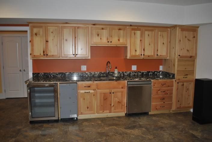 Wooden cabinets and countertop in a kitchen area with appliances against an orange backsplash.