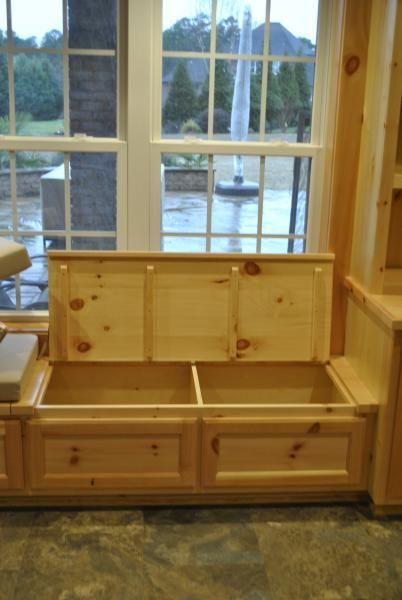 Wooden bench with storage compartments beneath a window overlooking a fountain.