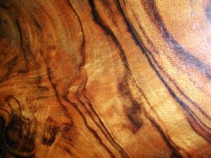 Close-up of polished wood surface with swirling dark and light brown patterns.