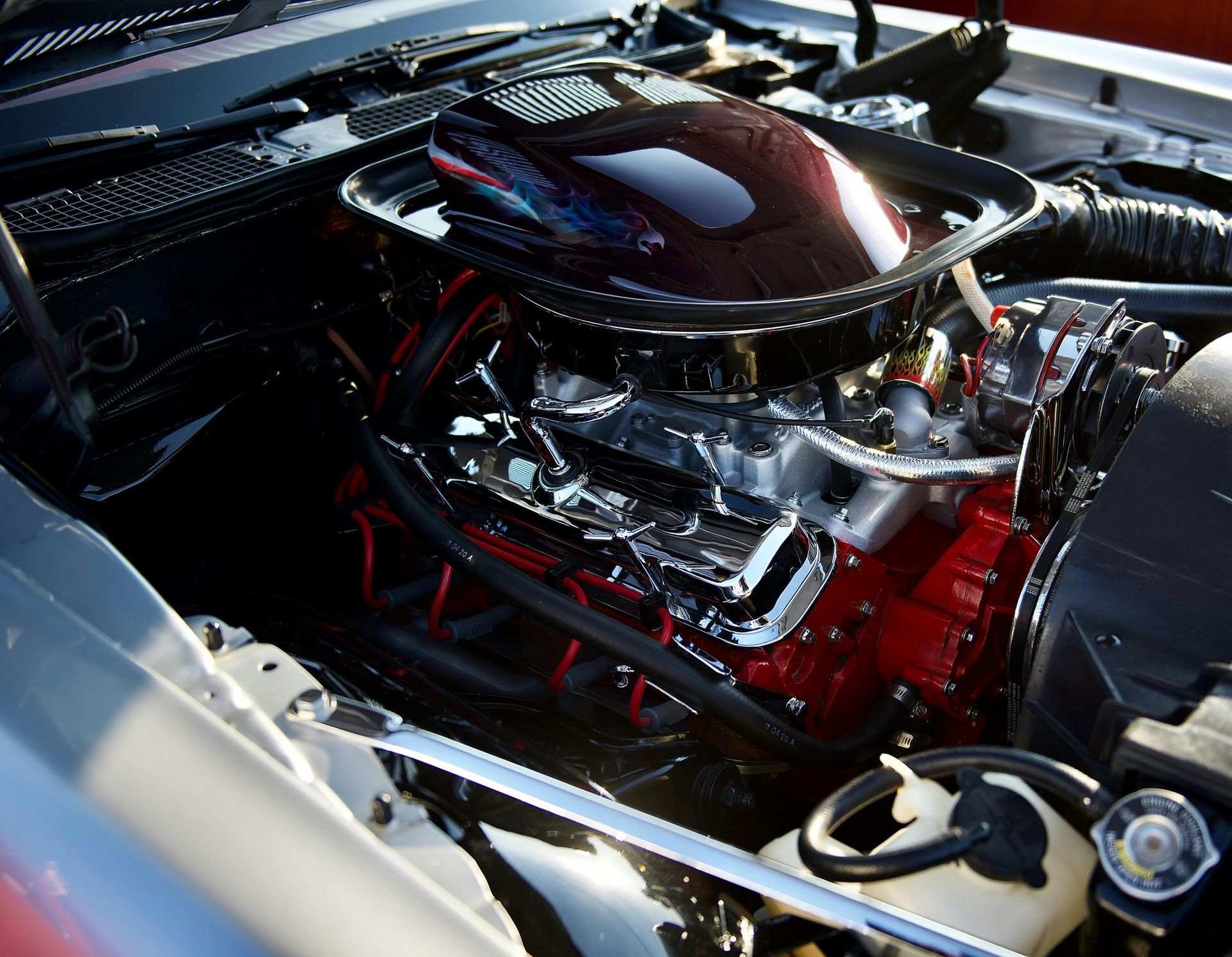 A close-up of a detailed car engine with a black air cleaner and a bright red engine block.