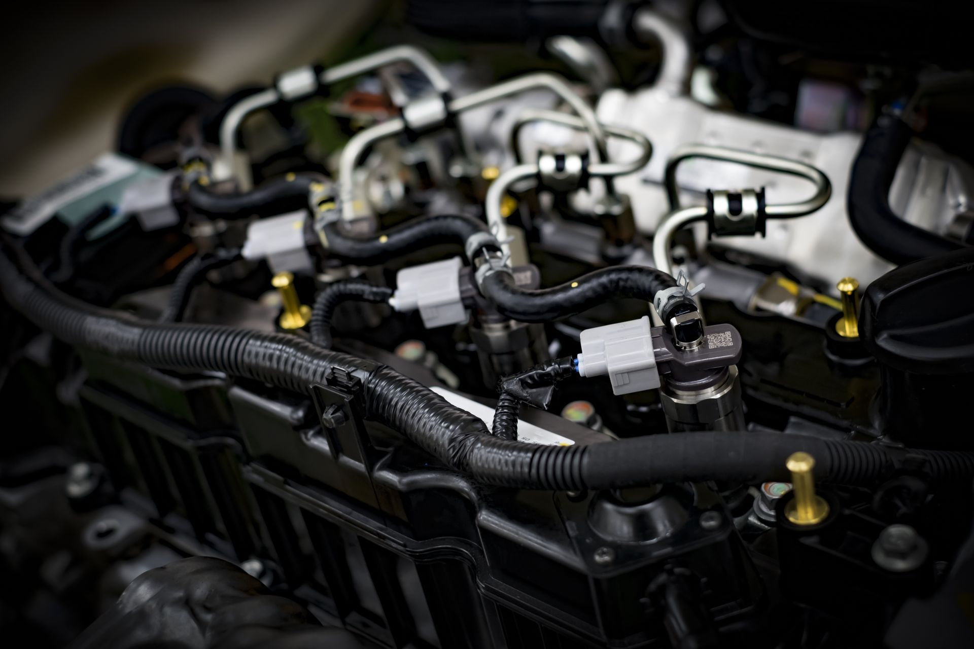 A close-up view of a modern internal combustion engine, highlighting metal fuel lines, injectors, and electrical wiring.