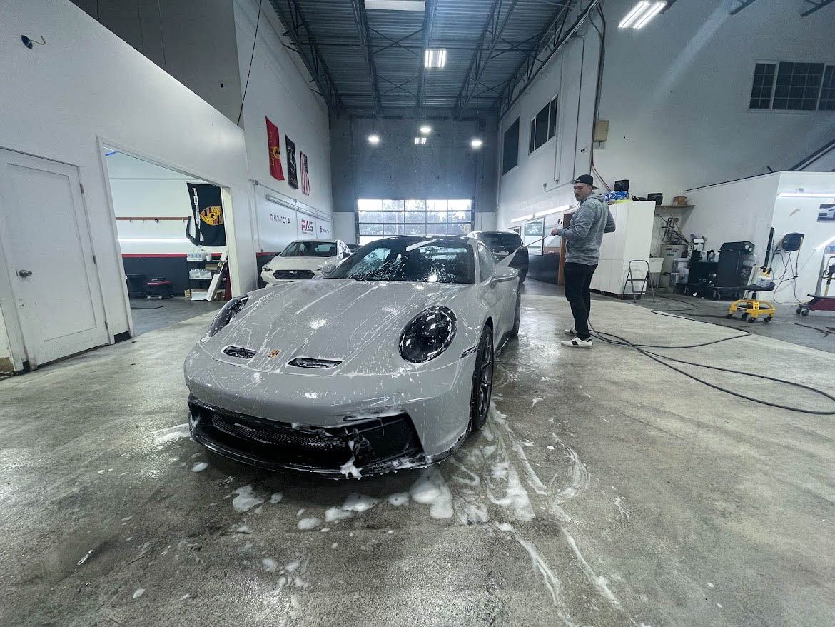 A man is washing a car in a garage.