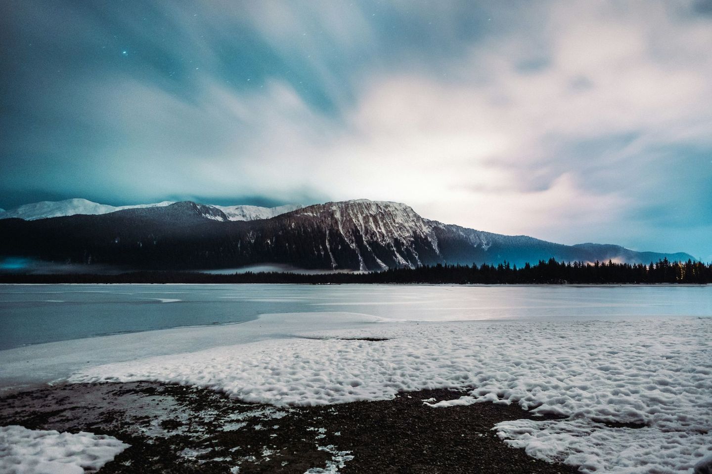 A snowy landscape with mountains in the background and a lake in Juneau AK. Local Tour Guide Jeff Hoover