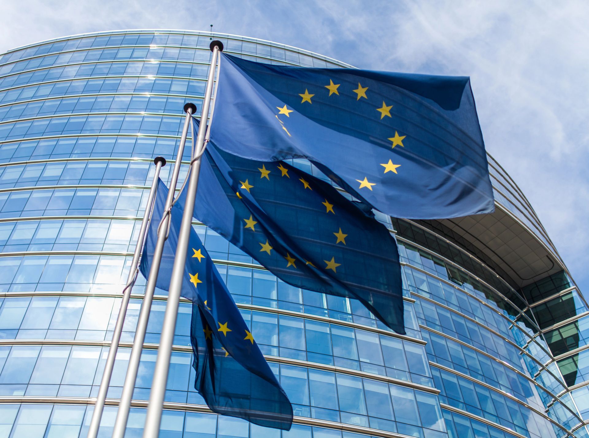 Bandiere dell'UE davanti a un moderno edificio per uffici in vetro.