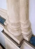 Base di colonna in pietra bianca con modanature decorative e finiture grigio-blu su una scala o una sporgenza architettonica.