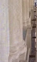 Primo piano di una tenda beige appesa accanto a una mensola o un ripiano in metallo.