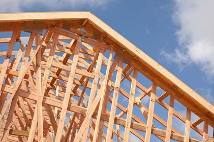 Wooden roof trusses against a blue sky, framing the structure of a new building.