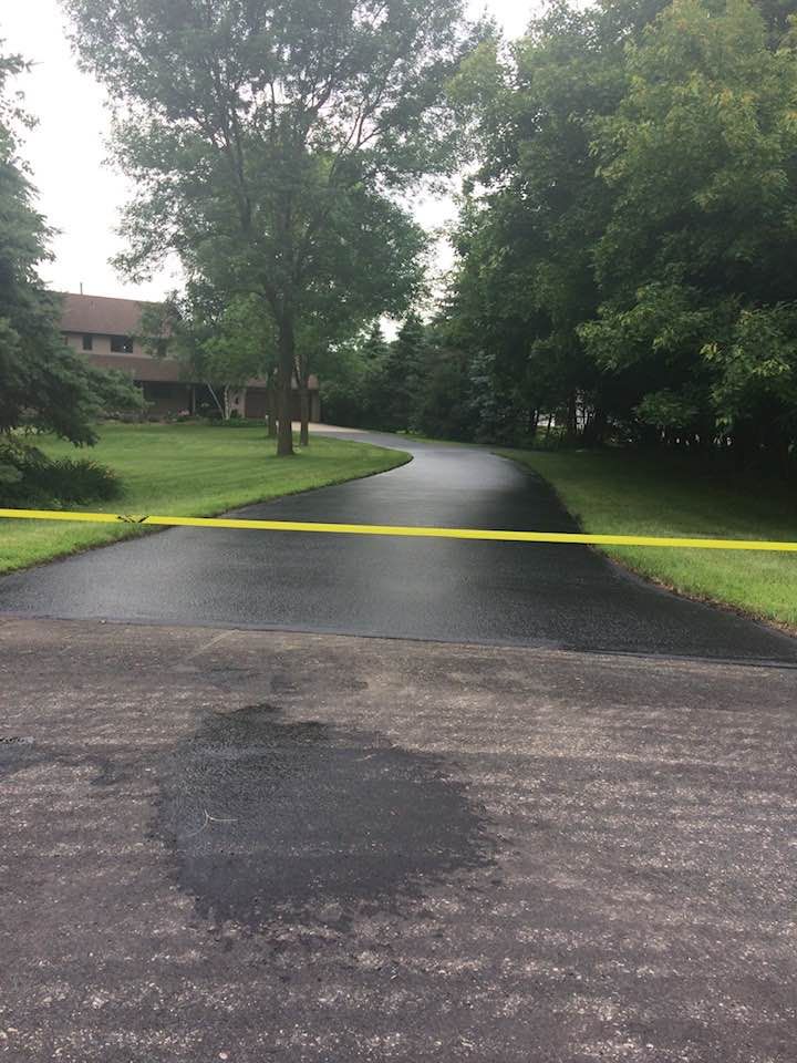 A residential driveway with a yellow tape on the side of it.