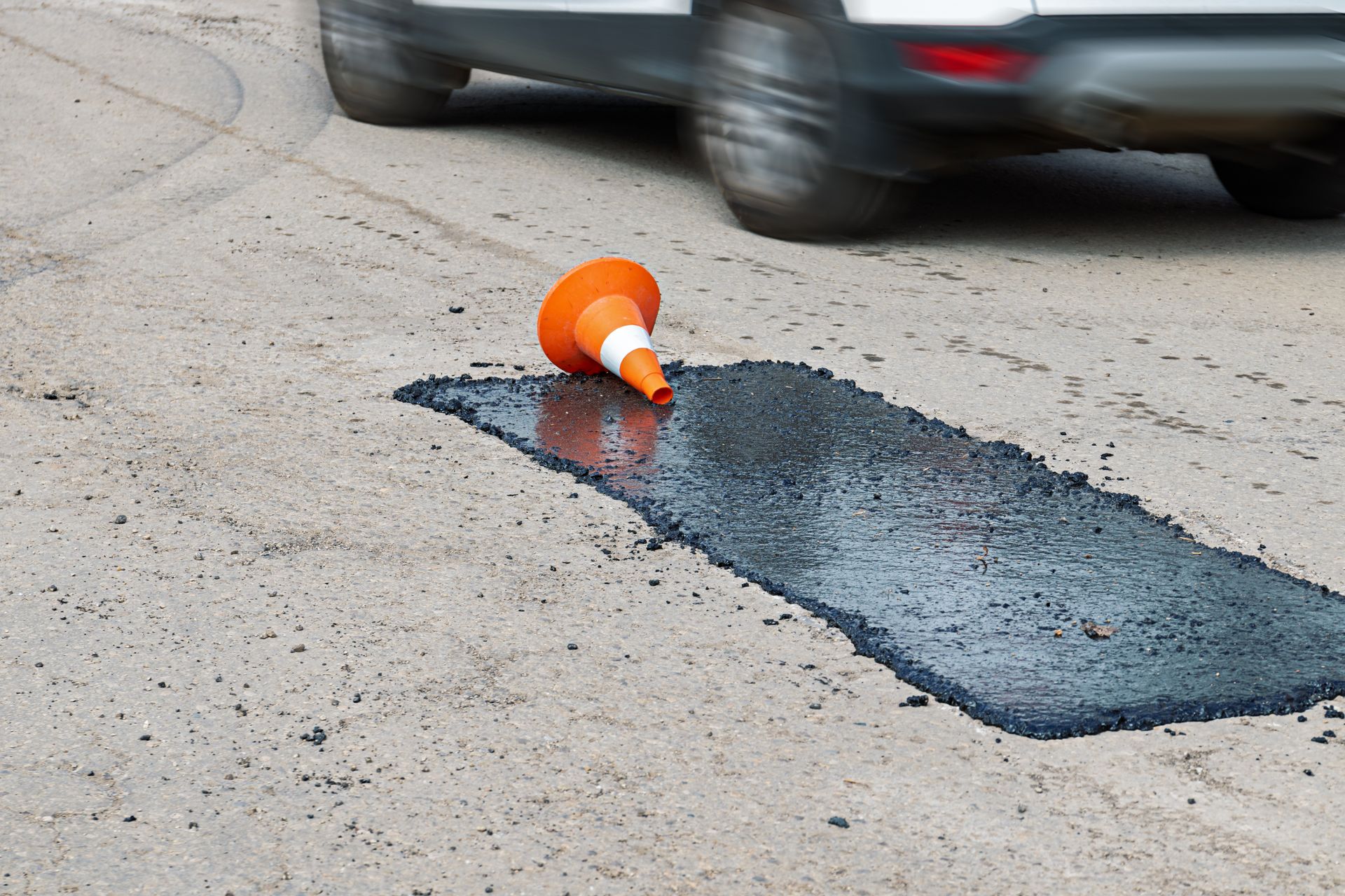 A car is driving past a pothole on the road.