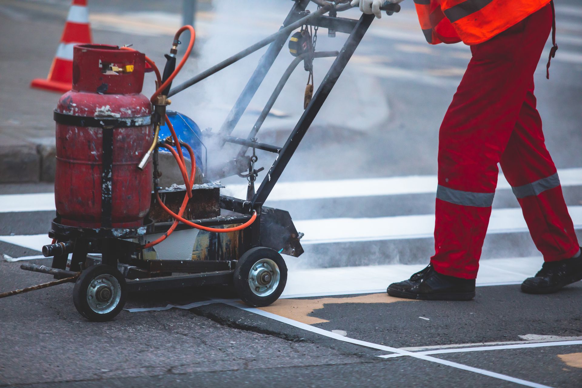 A man is using a machine to paint a crosswalk.