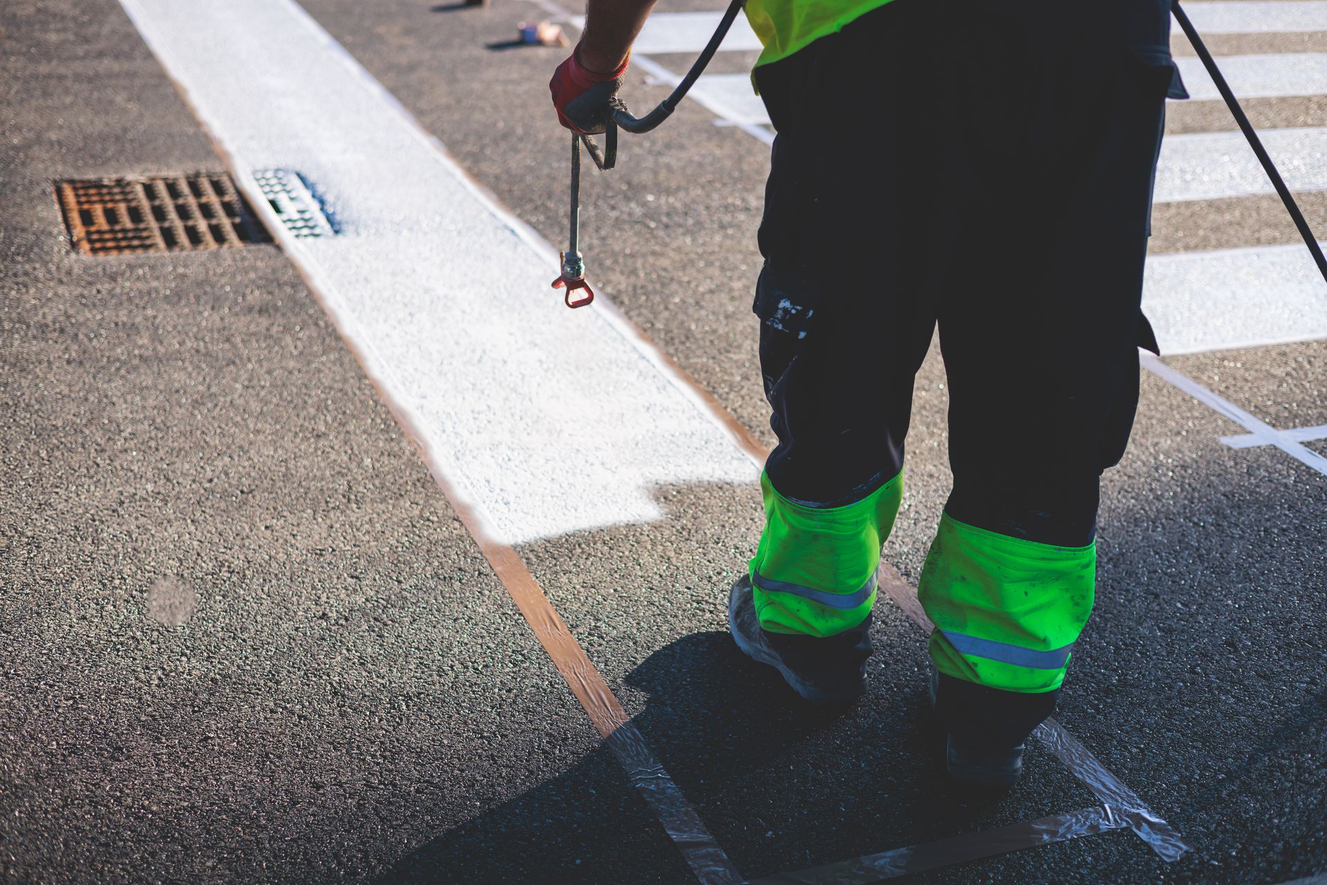 A man is spraying white paint on a crosswalk.