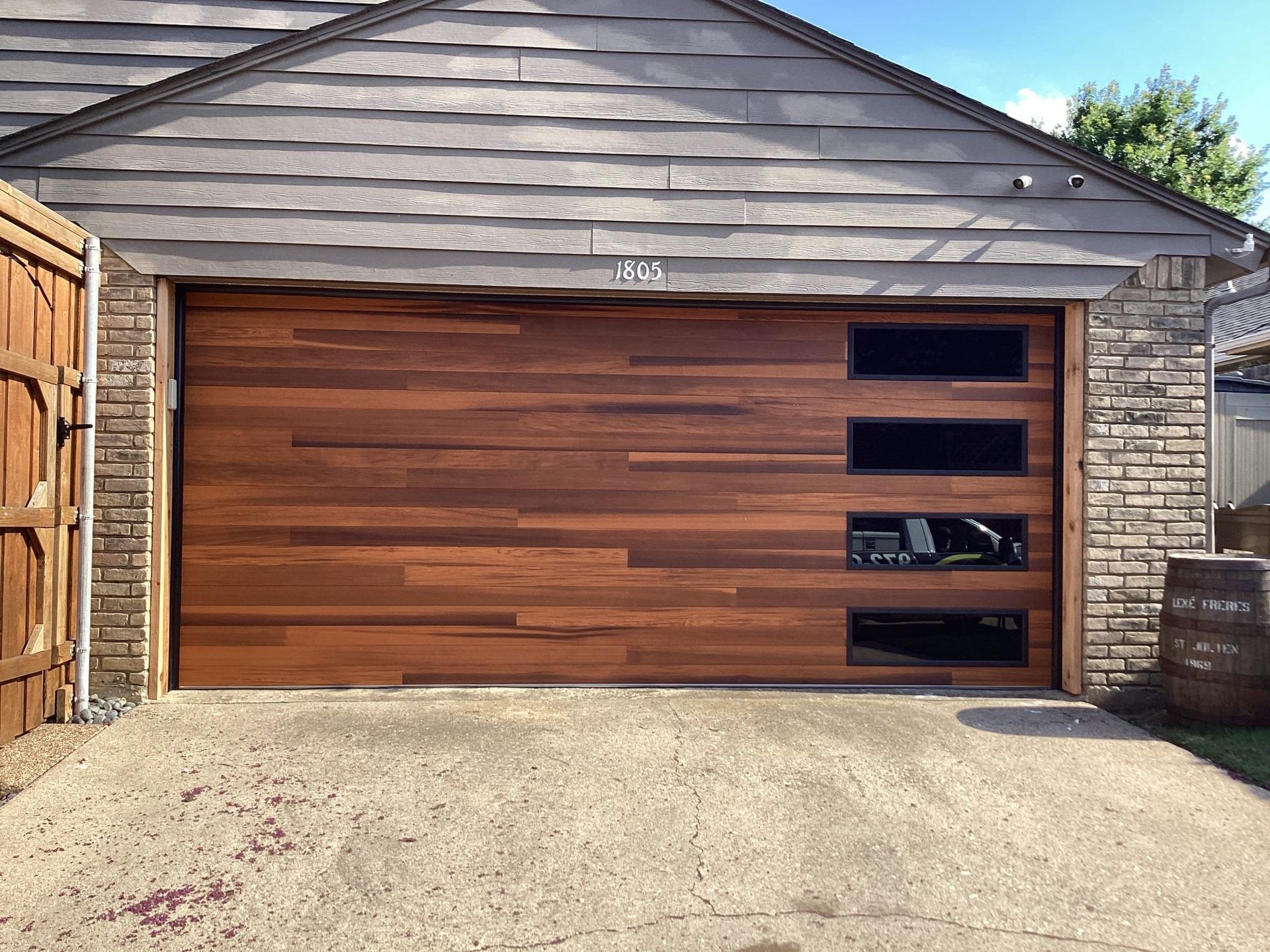 A modern garage door made of horizontal wood planks with a vertical stack of four rectangular glass windows on the right.