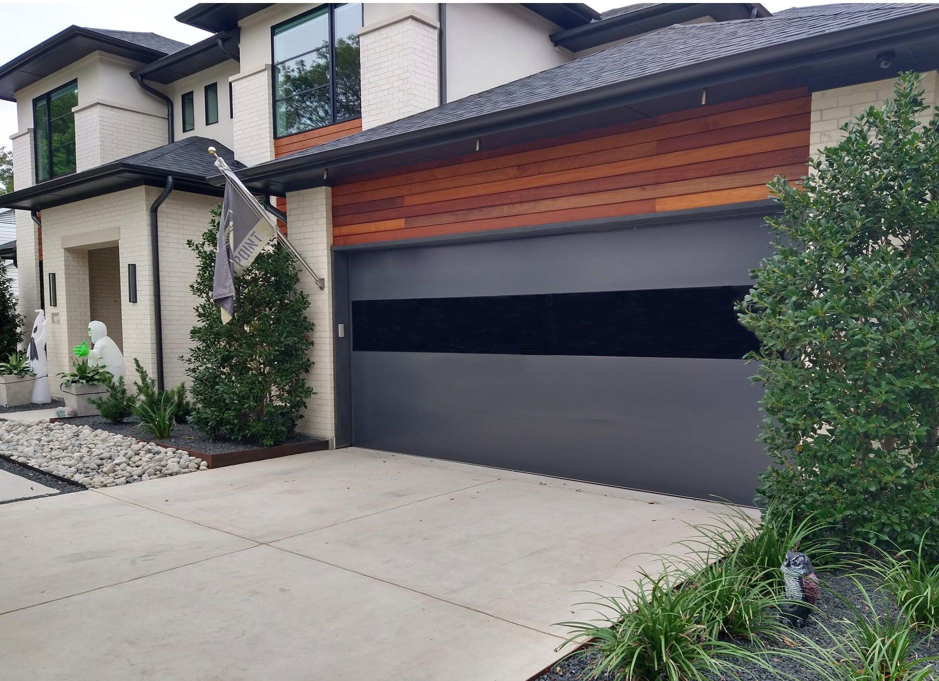 A modern house with a light-colored stone exterior, a wooden accent wall, and a large, dark gray garage door.