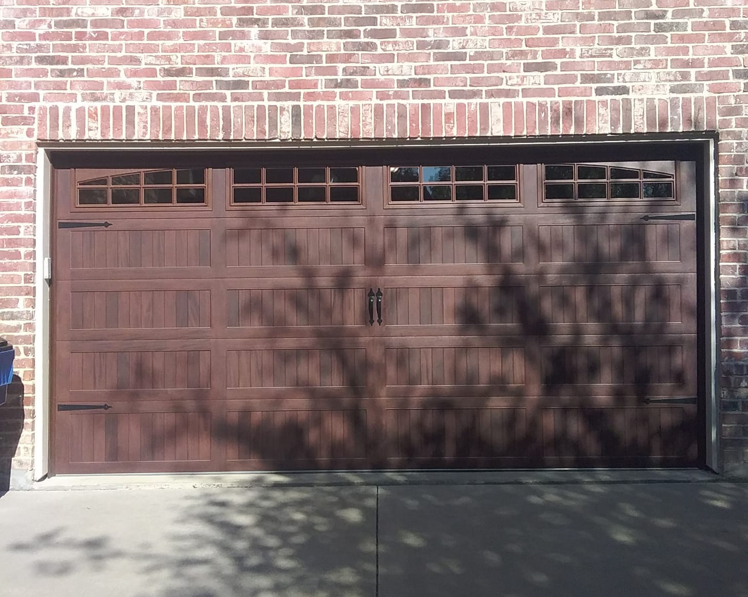 Brown garage door with windows, in a brick building.