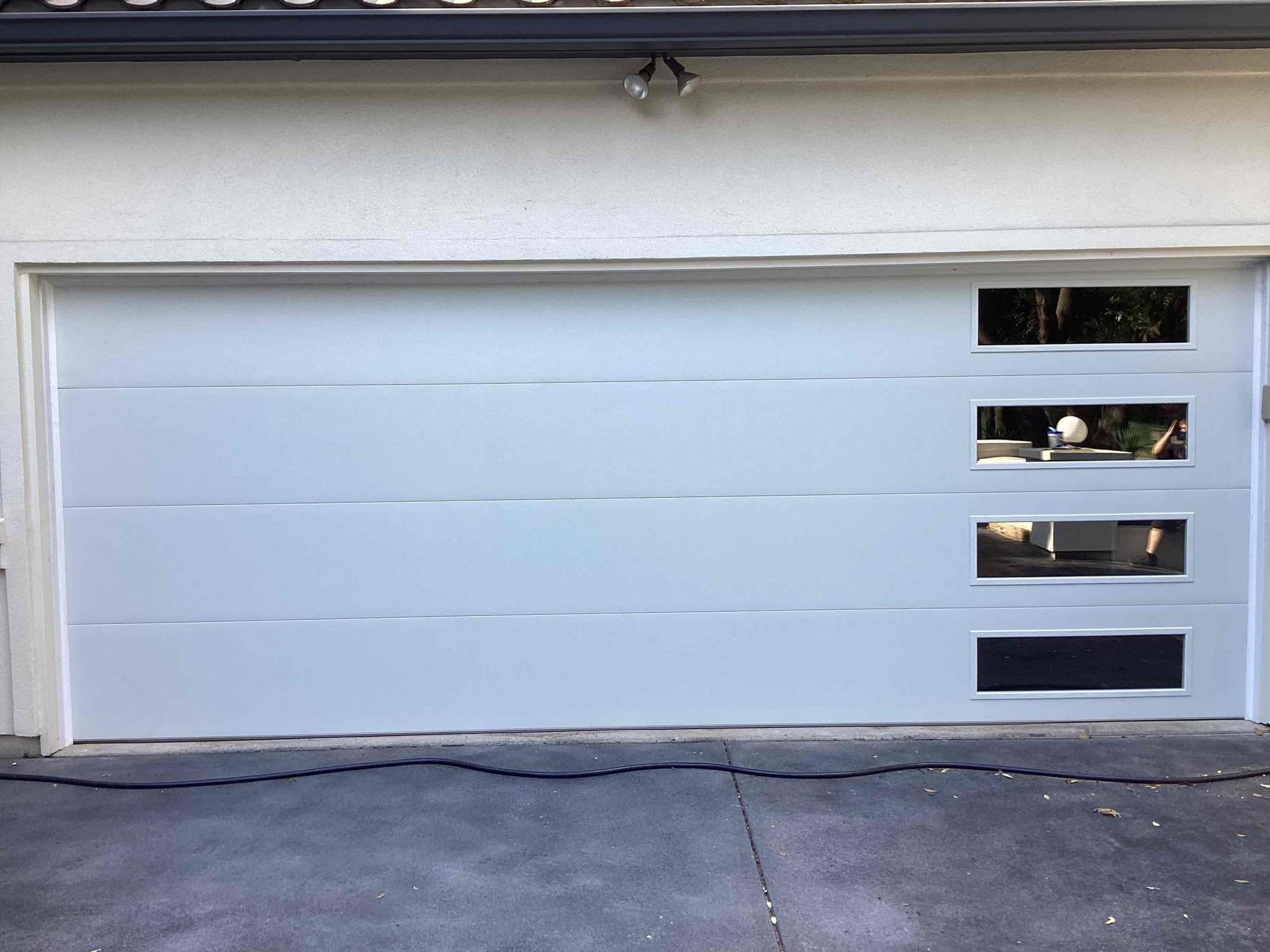 A white residential garage door with a column of four rectangular windows on the right side.