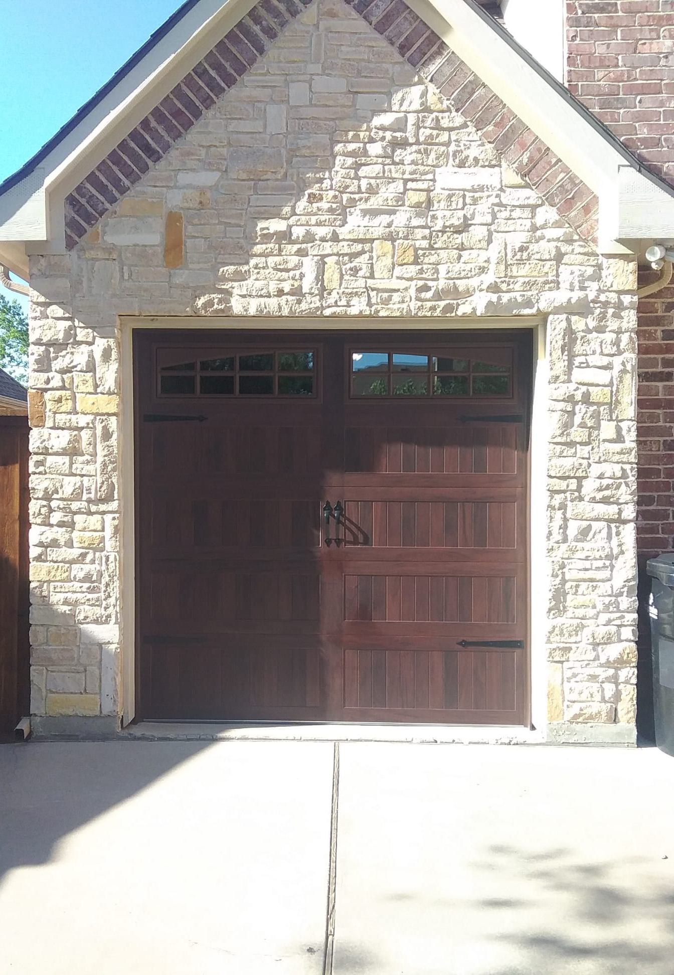 Brown garage door with windows, accented by a stone facade.