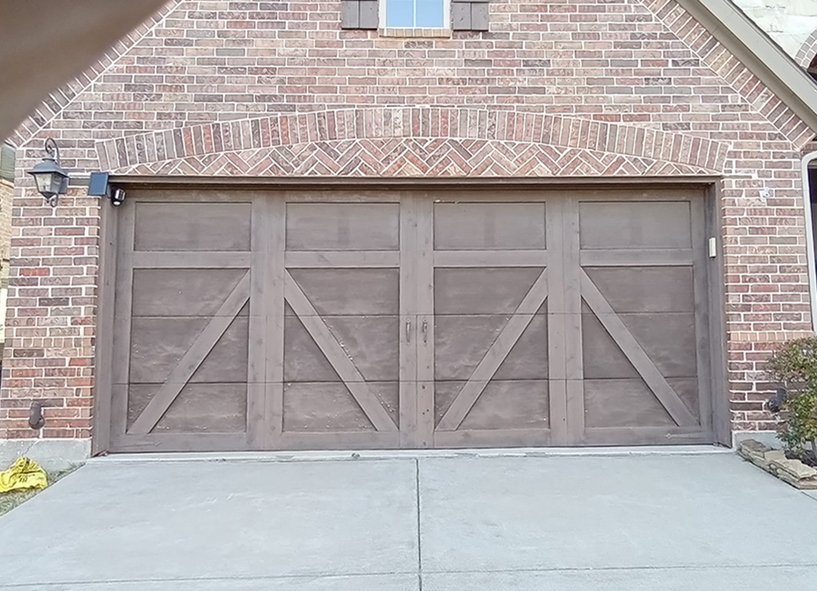 Brown garage door with diagonal accents, set in a brick facade, driveway in front.