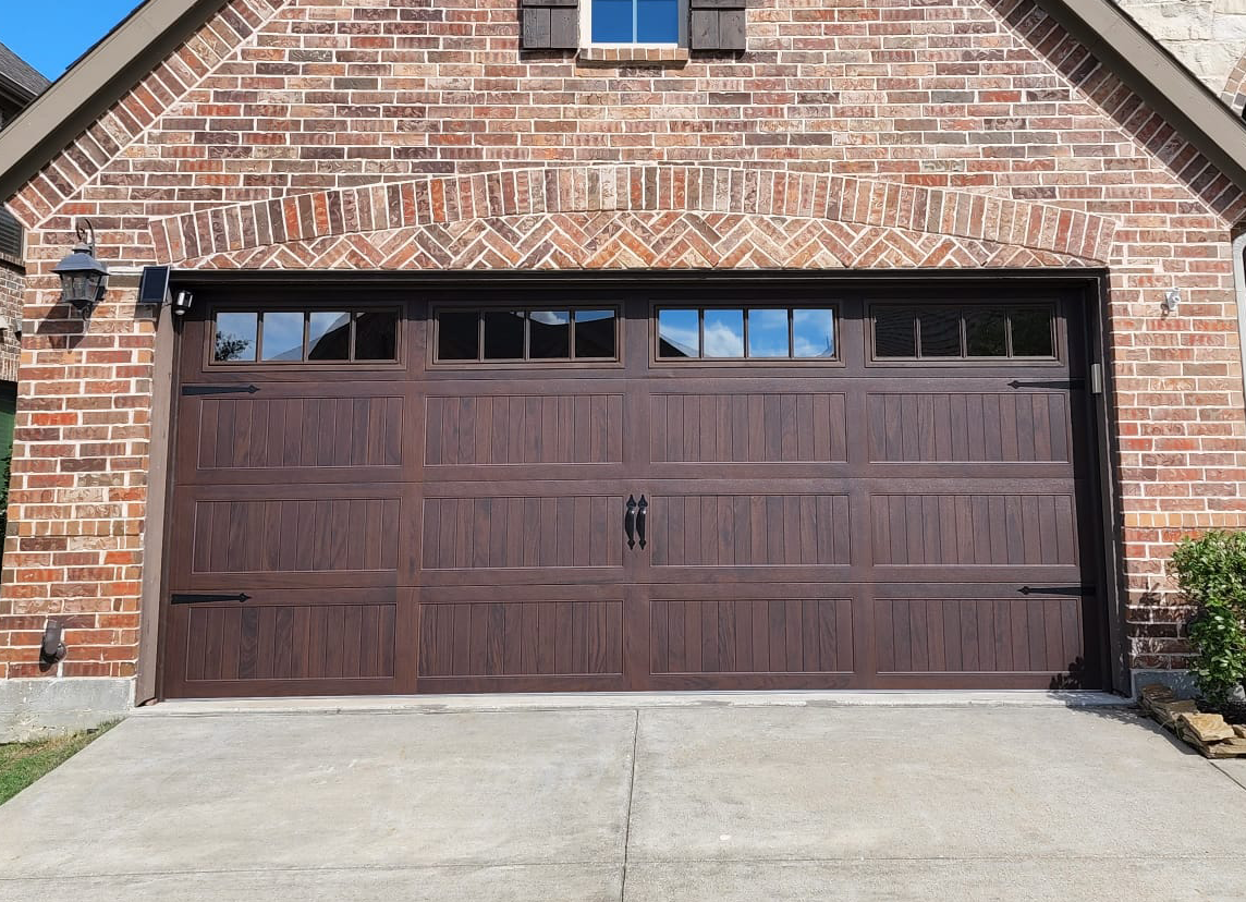 Brown garage door on a brick house with a concrete driveway.