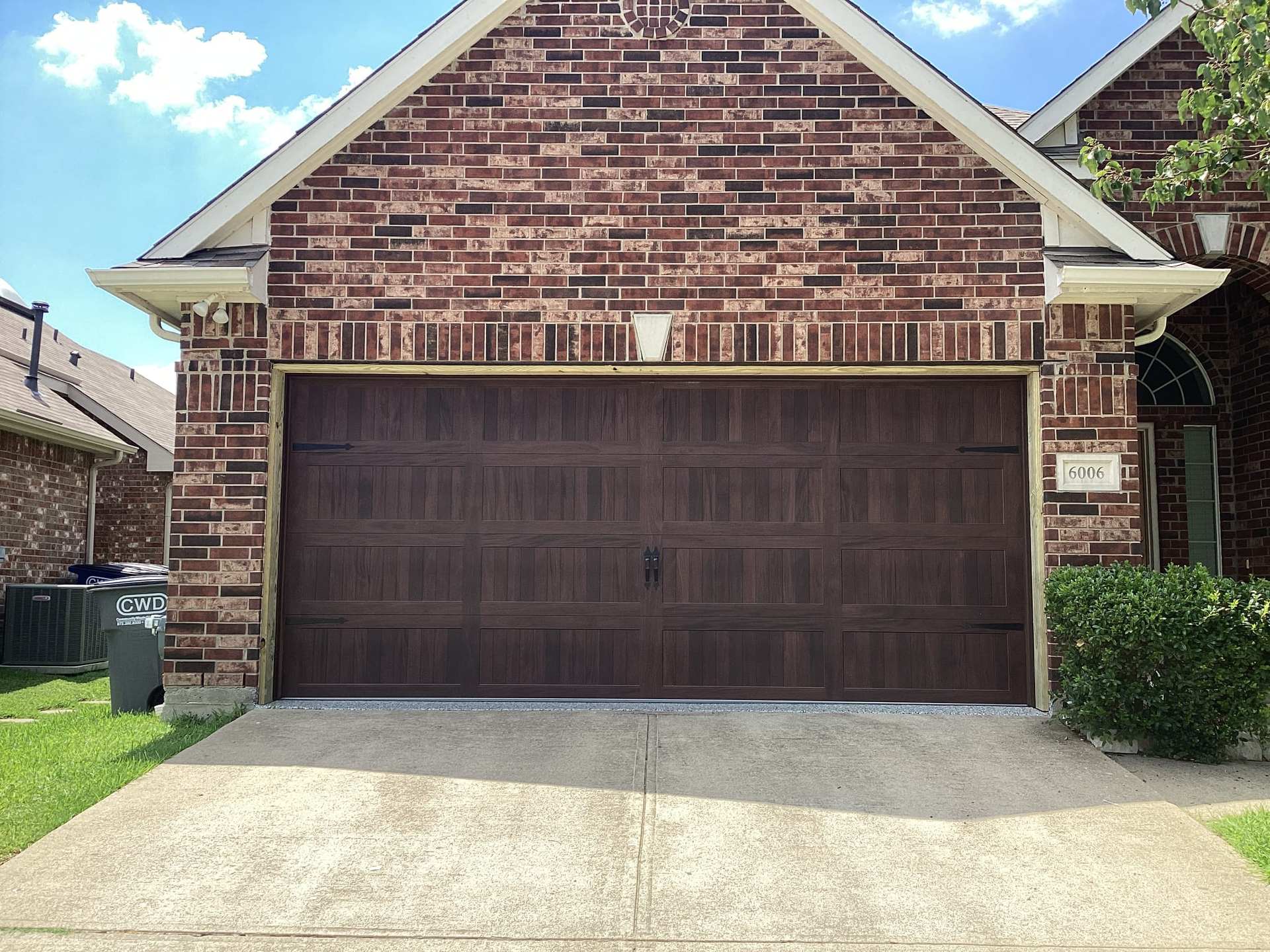 Brown garage door with brick facade.