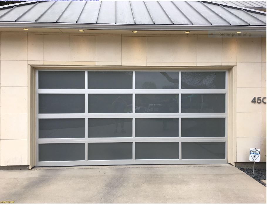 A modern residential garage door with four horizontal rows of frosted glass panels set in a light-colored metal frame.
