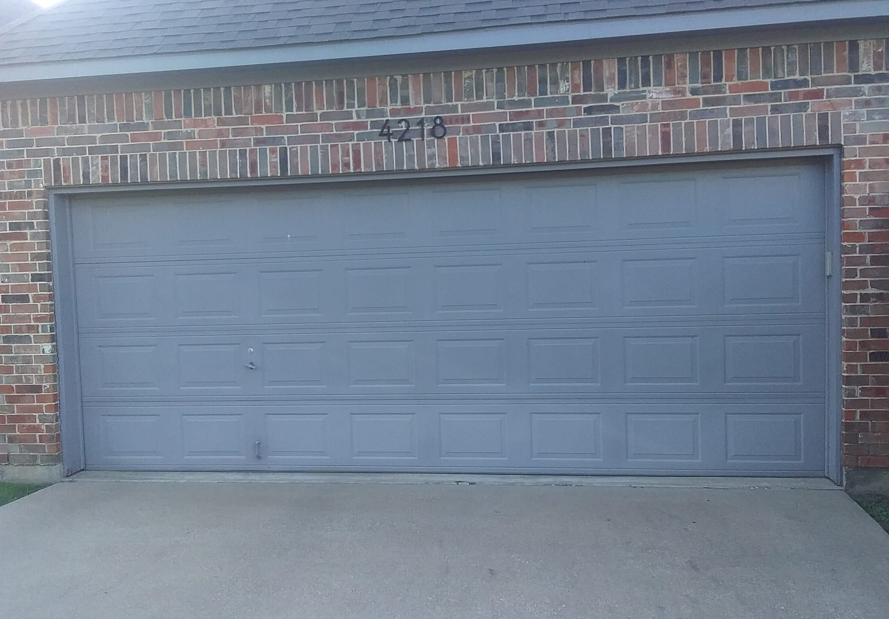 Gray garage door with address numbers 4213, brick exterior.