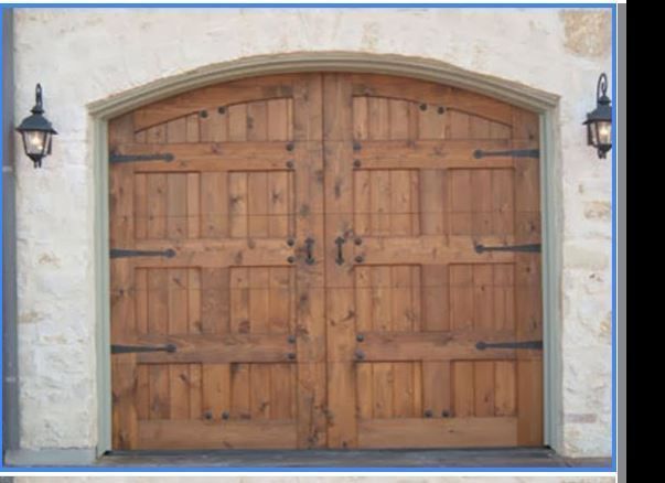 Arched, double wood garage door with rustic metal hinges and handles, set into a light-colored stone wall.