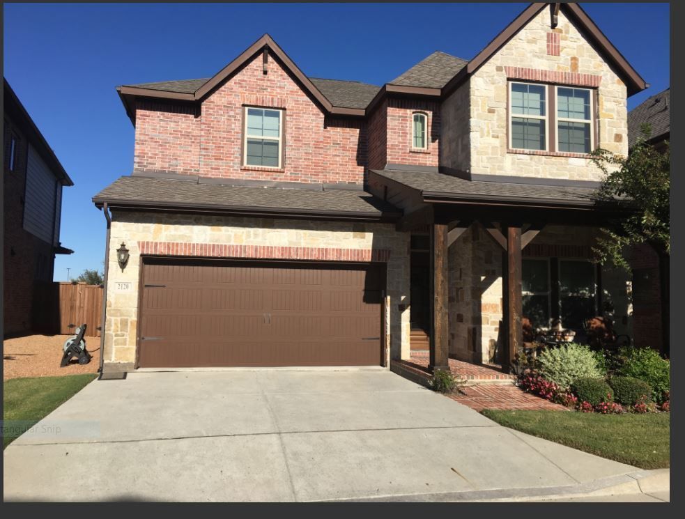 Two-story house with a brick and stone facade, a brown two-car garage, and a concrete driveway on a sunny day.