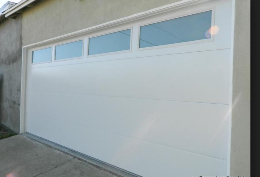 White residential garage door with a row of four rectangular windows along the top panel.