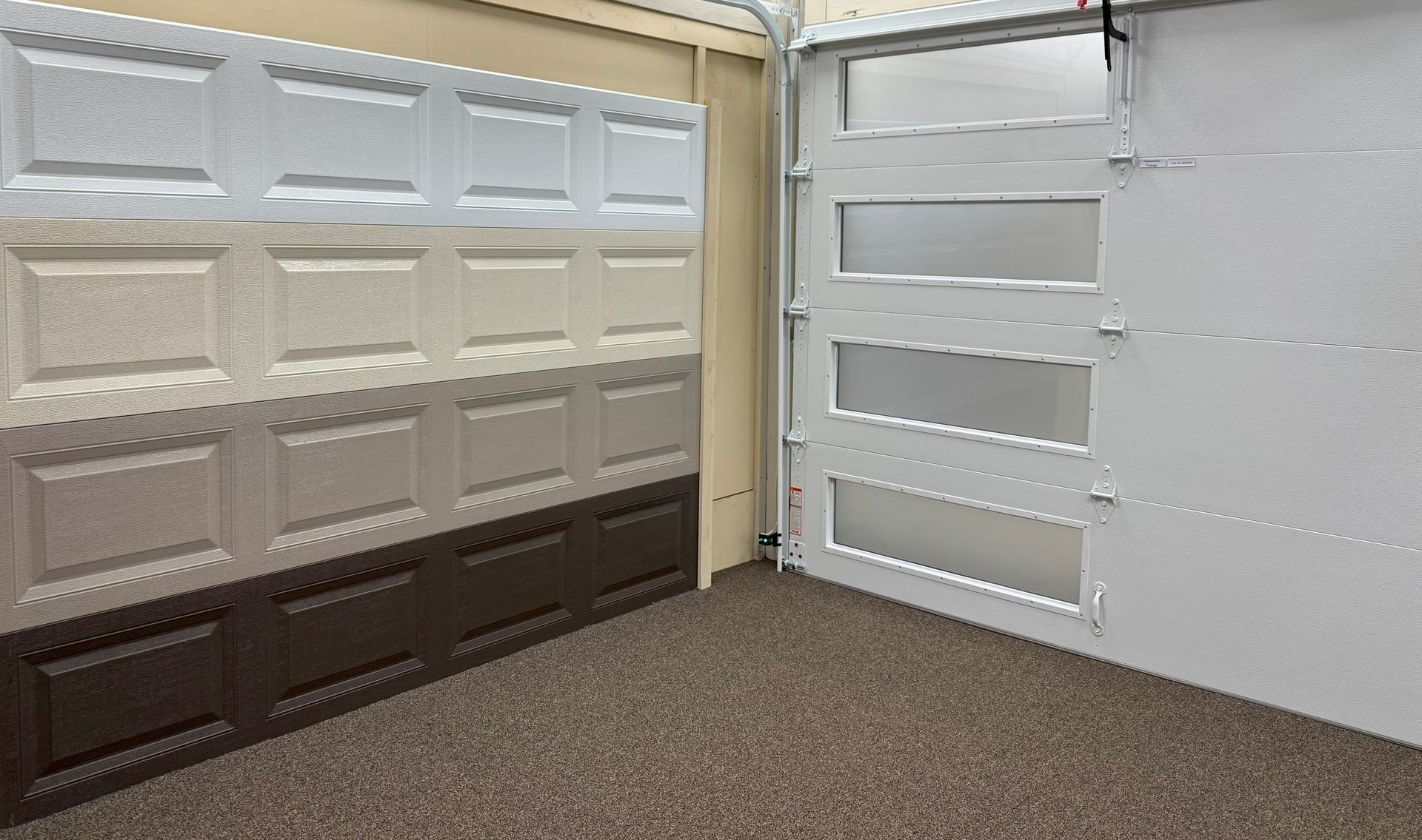 Garage interior with sample garage doors in various colors. One door has frosted glass panels.